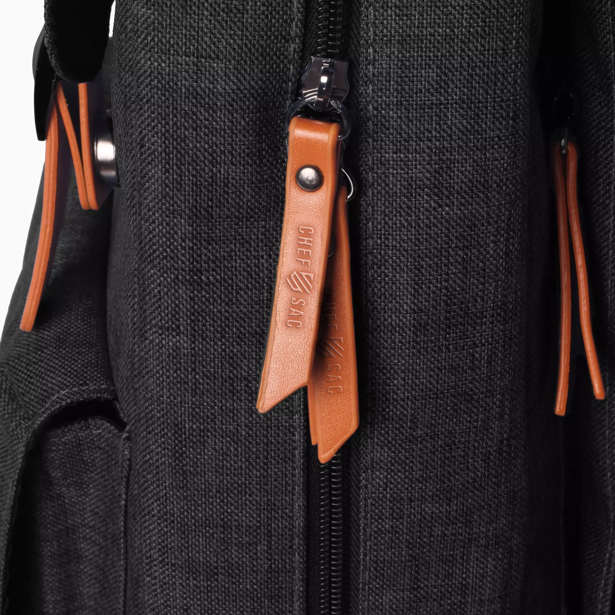 Close-up of a black backpack with brown leather zipper pull and 'Chef Sac' branding.