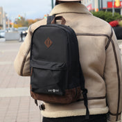Person wearing a black backpack with brown leather accents on a city street and visible branding, 'Chef Sac'