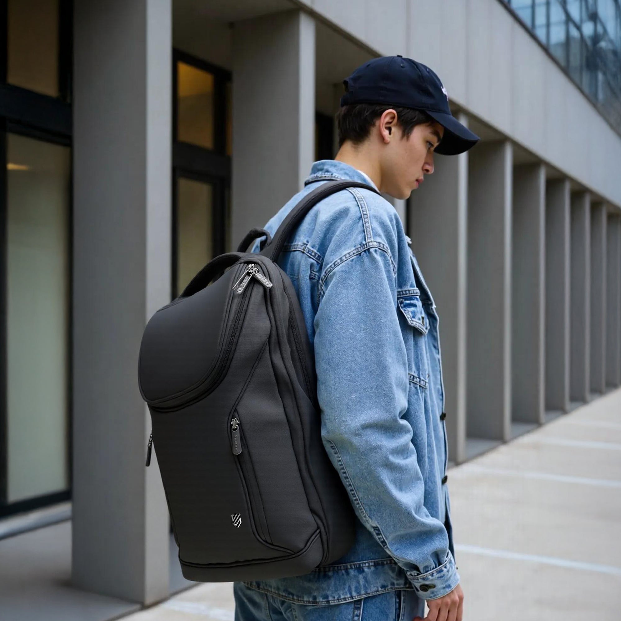 Person wearing a black chef backpack  with Chef Sac logo and blue denim jacket in an urban setting